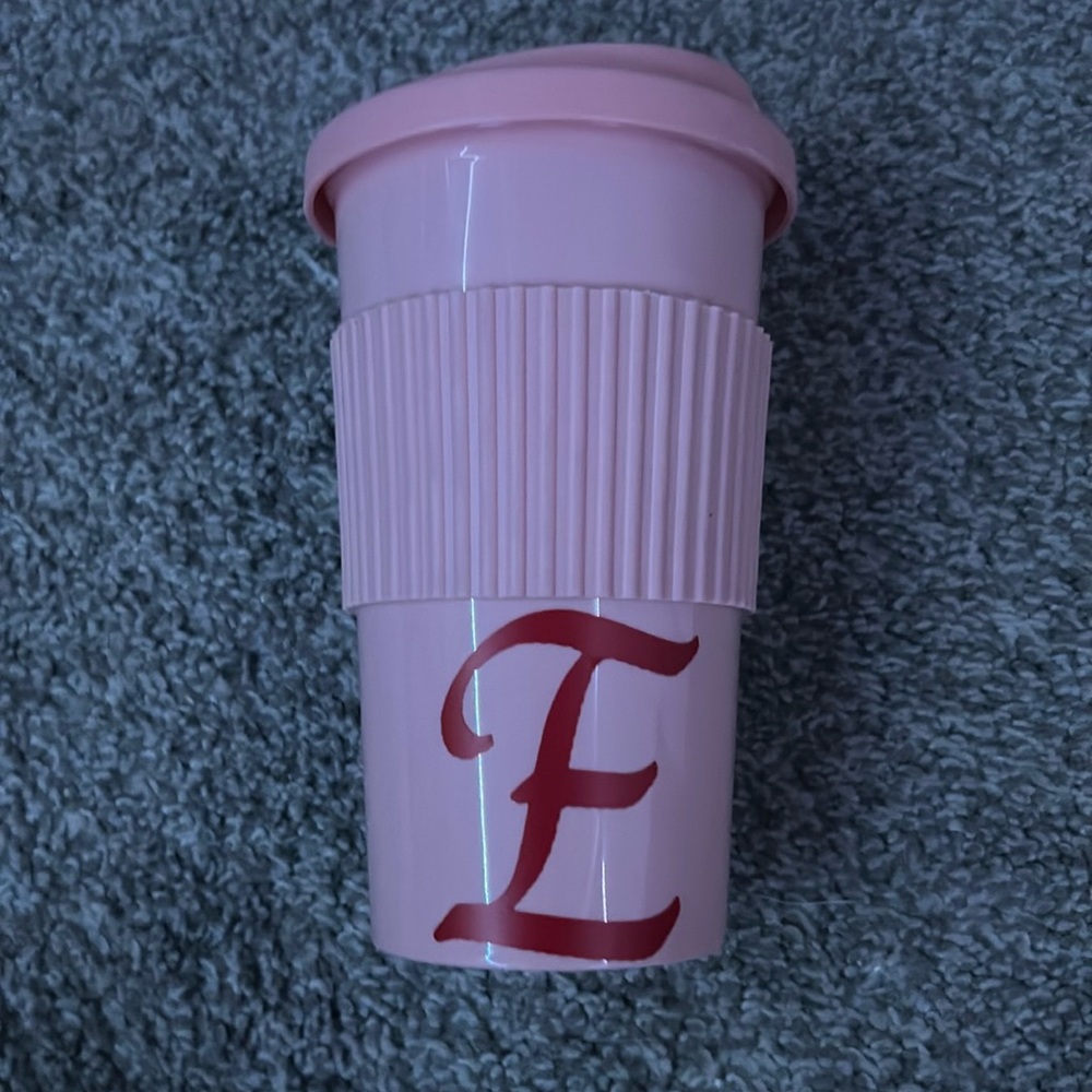A cup pink cup with a pink E